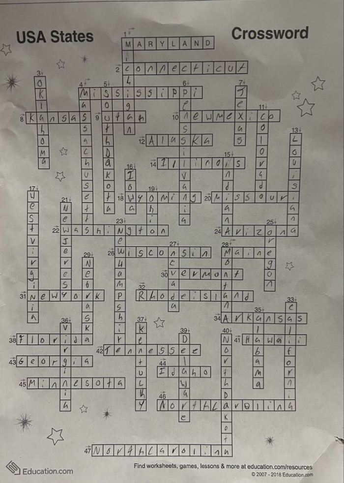 Fourth grade student looking at a map to solve the USA states crossword puzzle worksheet