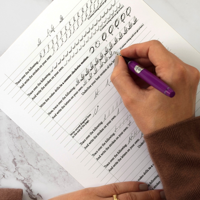 First grade student practicing cursive handwriting by writing their first and last name on a worksheet with dotted line guides
