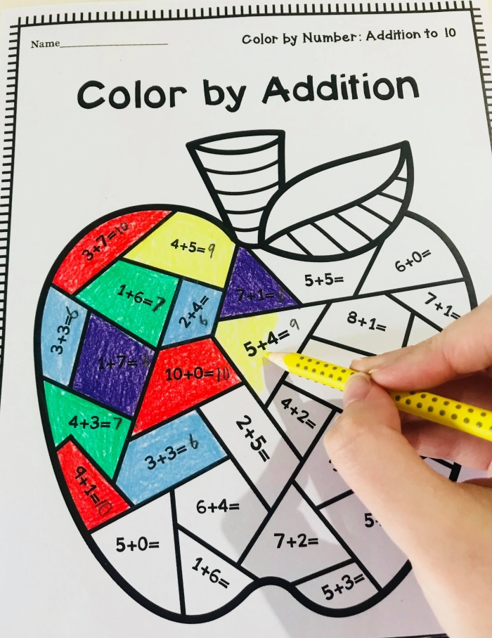 First grade student completing a color by addition facts worksheet featuring math problems to solve for a creative art reveal