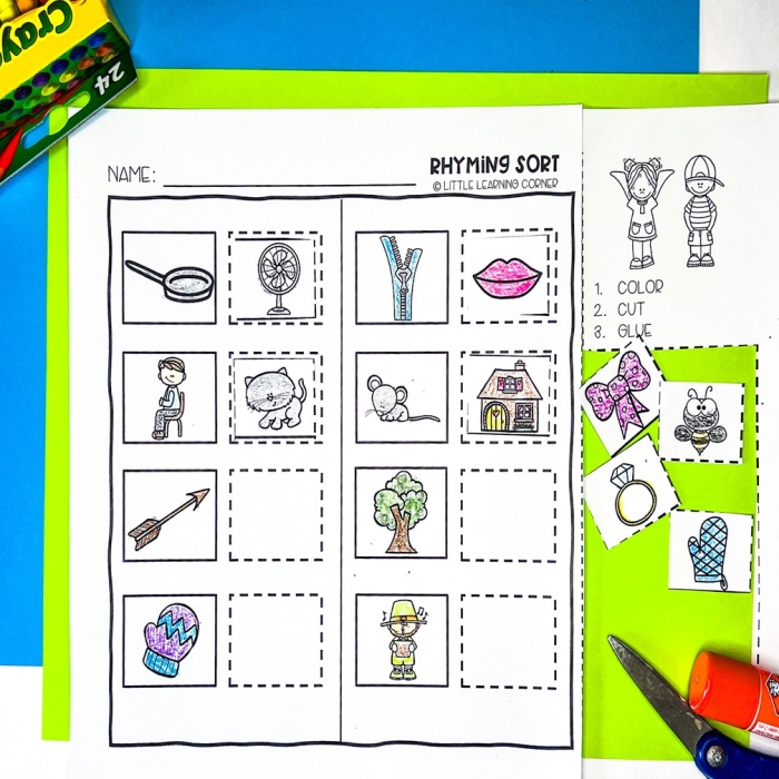 Kindergarten student cutting and pasting rhyming word pairs on a worksheet activity sheet