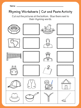 Kindergarten student cutting and pasting rhyming word pairs on a worksheet activity