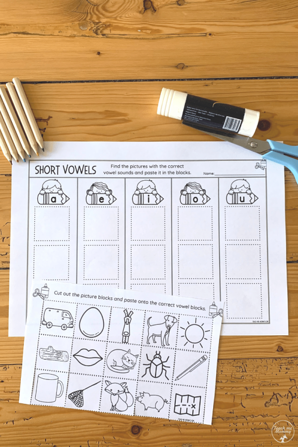 First grade student completing a Sort the Short Vowels cut and paste worksheet activity