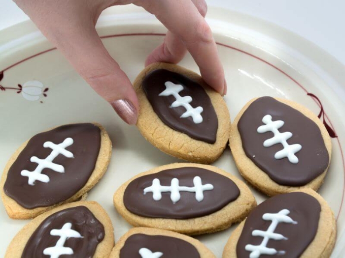 Engaging division activity for students to determine who baked the largest football cookie Football Cookie Measurement worksheet for third graders using rulers to measure cookie sizes