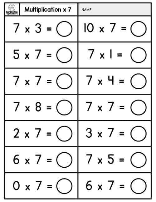 Third grade students working on a multiplying by seven math worksheet, solving equations and filling in a chart. A focused classroom scene featuring kids engaged in their multiplication practice.