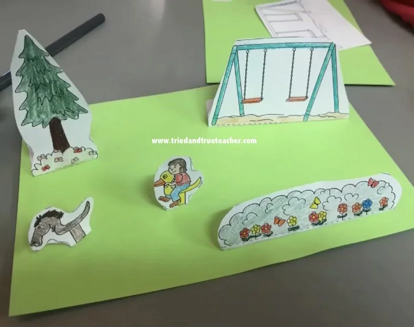 First grade pop-up park playground worksheet featuring swings, slides, and playful trees